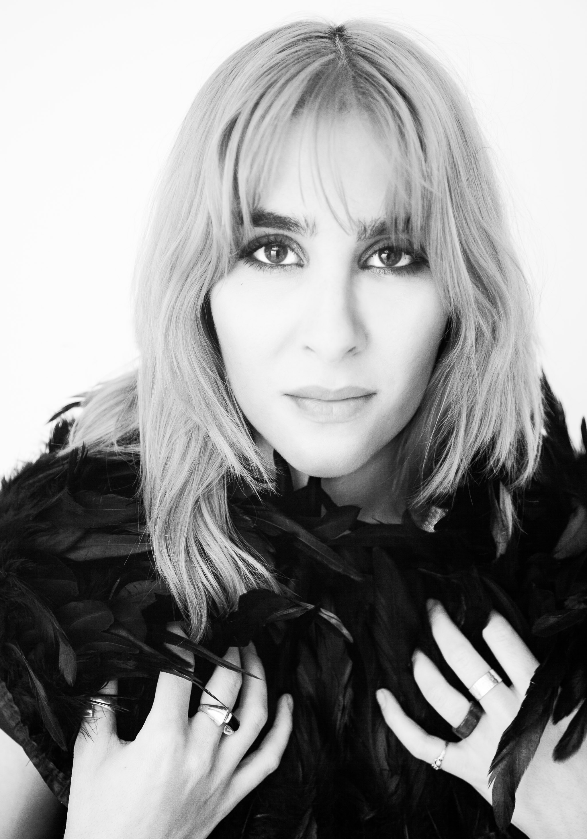 young woman with medium length hair passionate expression strong presence wearing feathered scarf