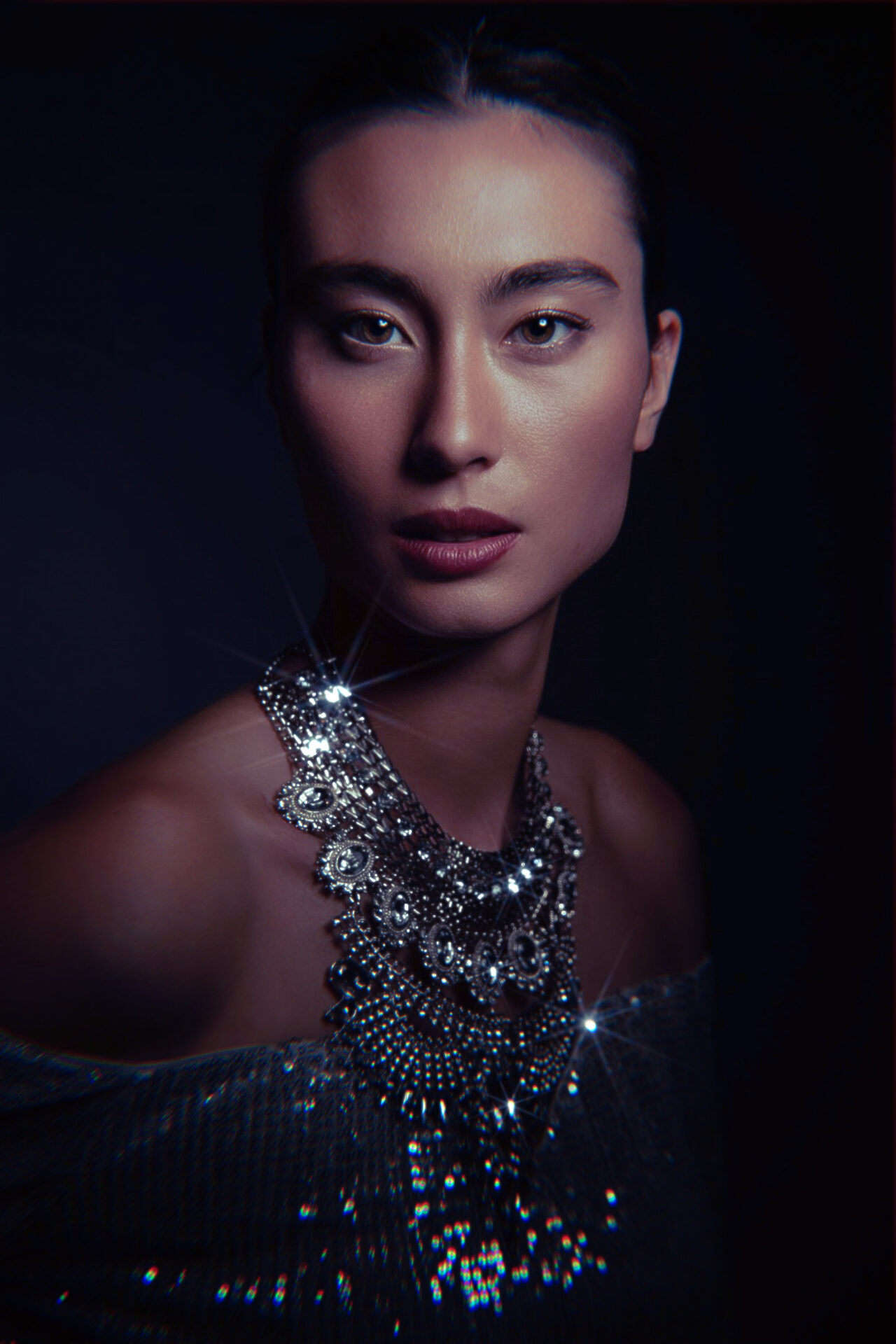 professional photo of beautiful asian model wearing oversized rhinestone necklace and silver sequins dress