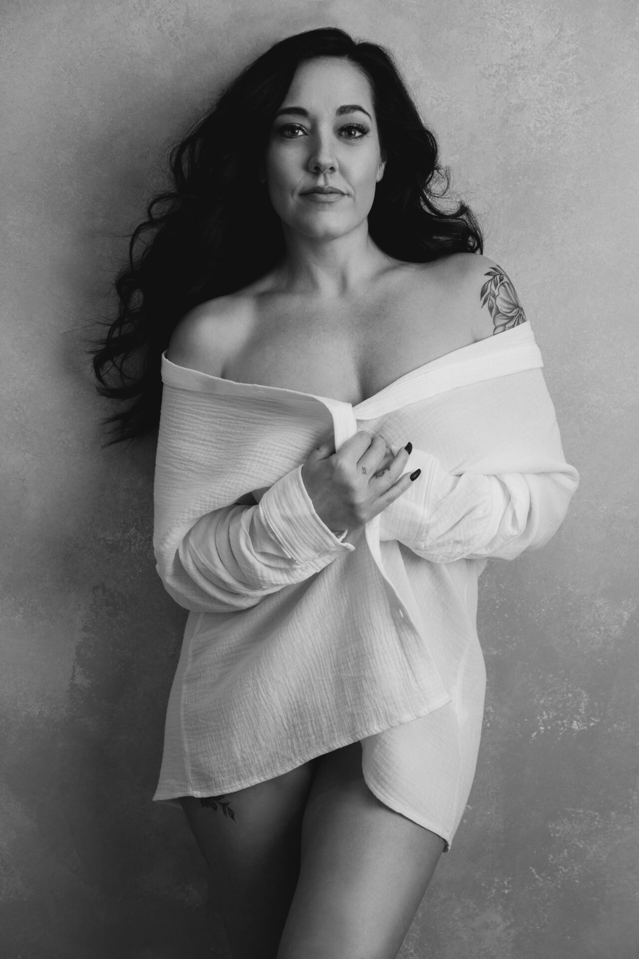 beautiful young woman with long black hair posing sensually for the camera wearing an oversized white button down shirt