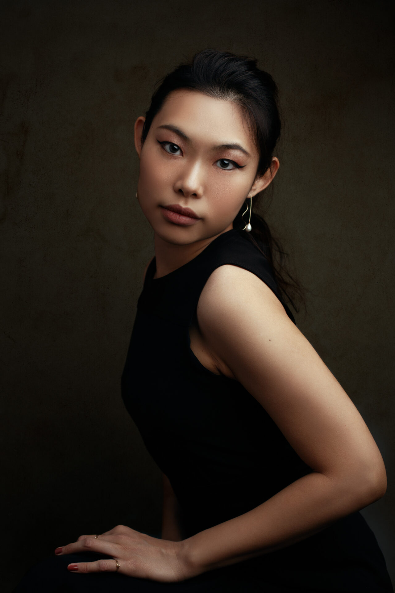 beautiful asian woman in a black sleeveless dress posing elegantly in a Farmingdale, New York photography studio
