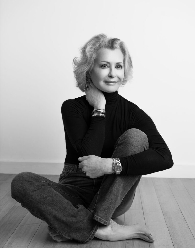 Black and white portrait of an elegant woman sitting on the floor with a relaxed pose, photographed at The BeVard Studio in Farmingdale, NY.