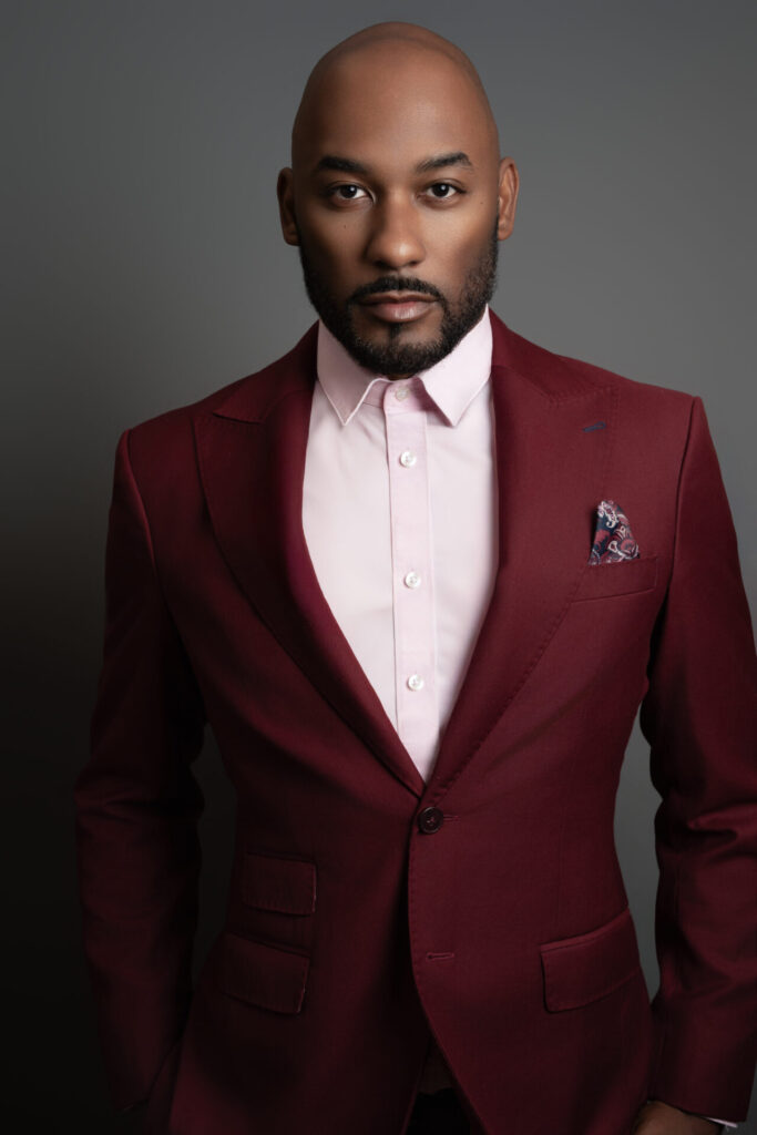 Dramatic portrait of a man in a burgundy suit posing for a modern editorial photo in a Farmingdale, NY studio.