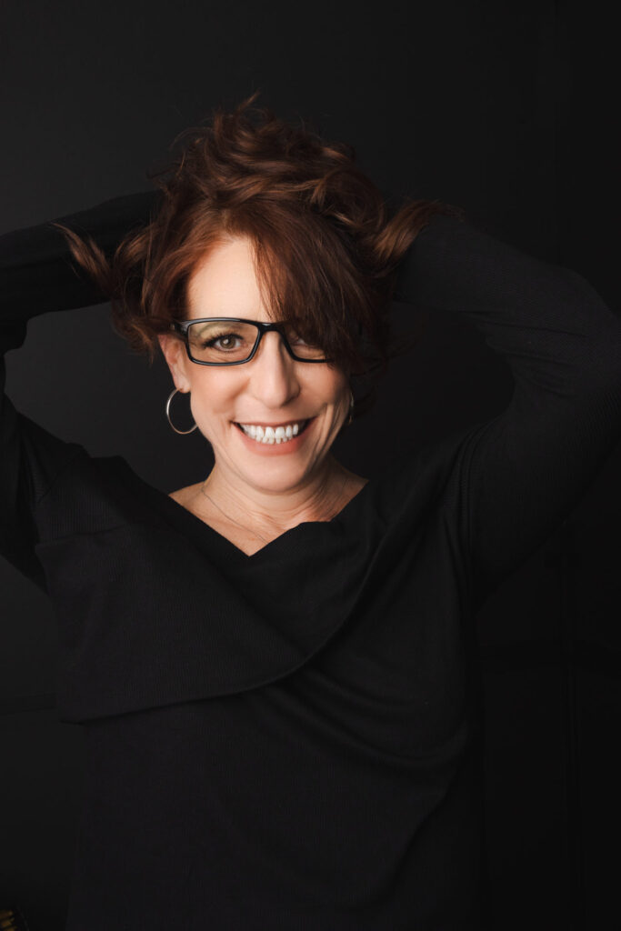 Personal branding portrait of a smiling woman with glasses wearing black, photographed at The BeVard Studio in Nassau County, New York