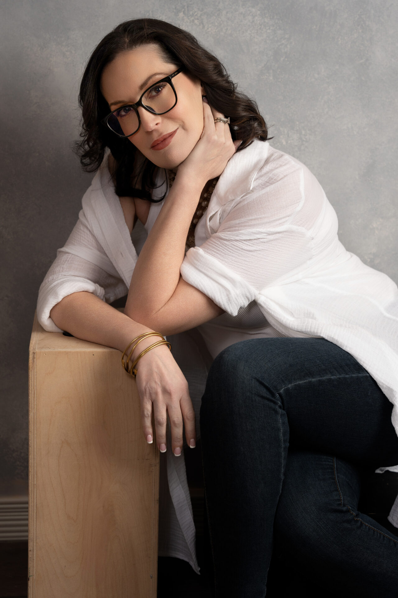 Personal branding portrait of a confident woman in glasses wearing a white shirt and jeans, photographed in The BeVard Studio on Long Island, NY.