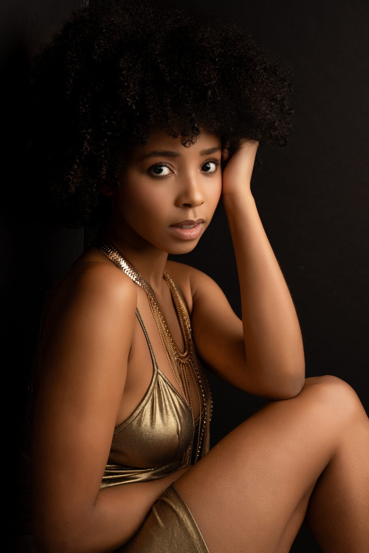 a editorial portrait of a woman wearing a gold dress posing gracefully at a long island luxury photo studio 