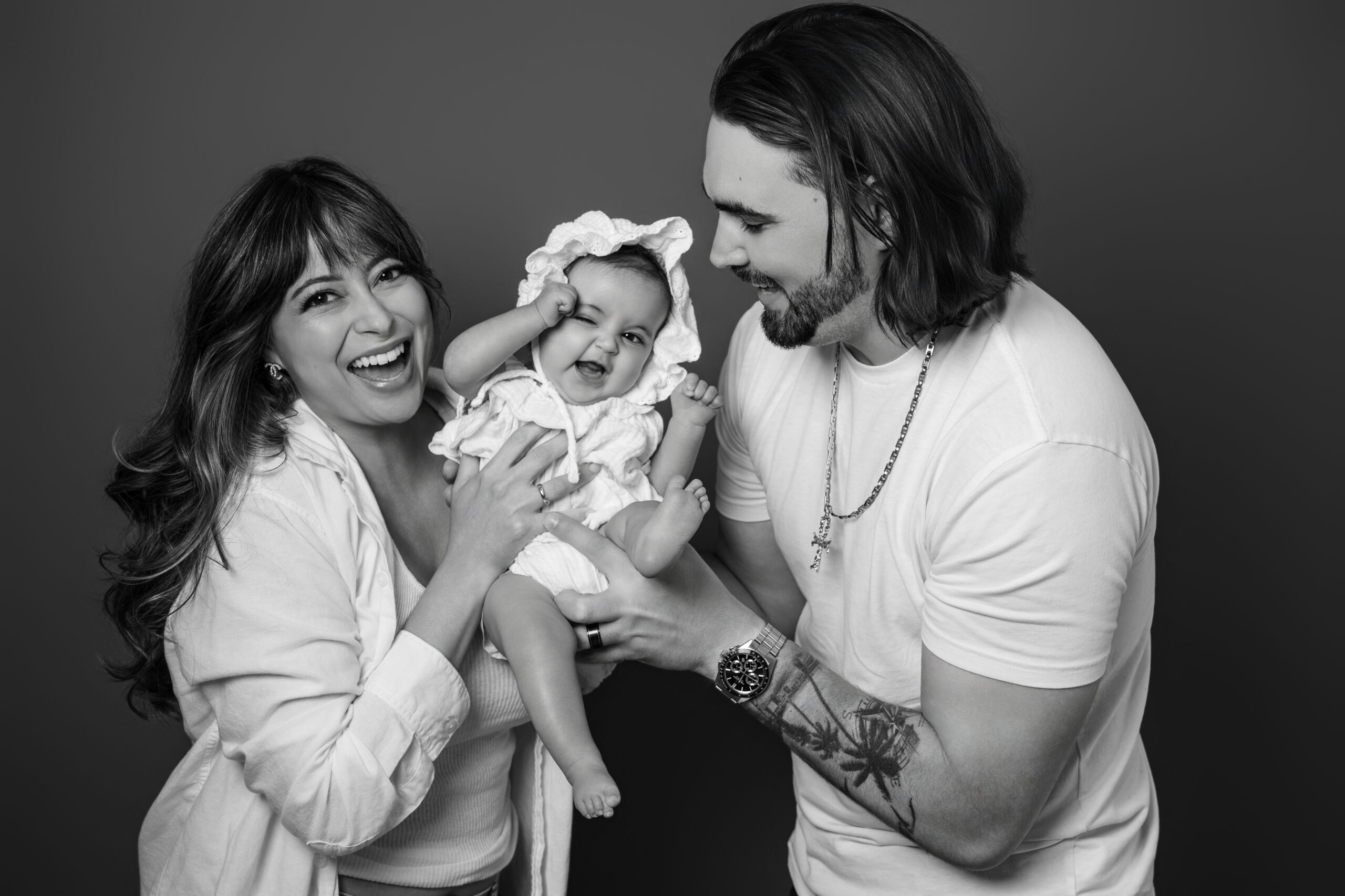 Mom and dad laughing with their baby in black and white, family portrait Long Island