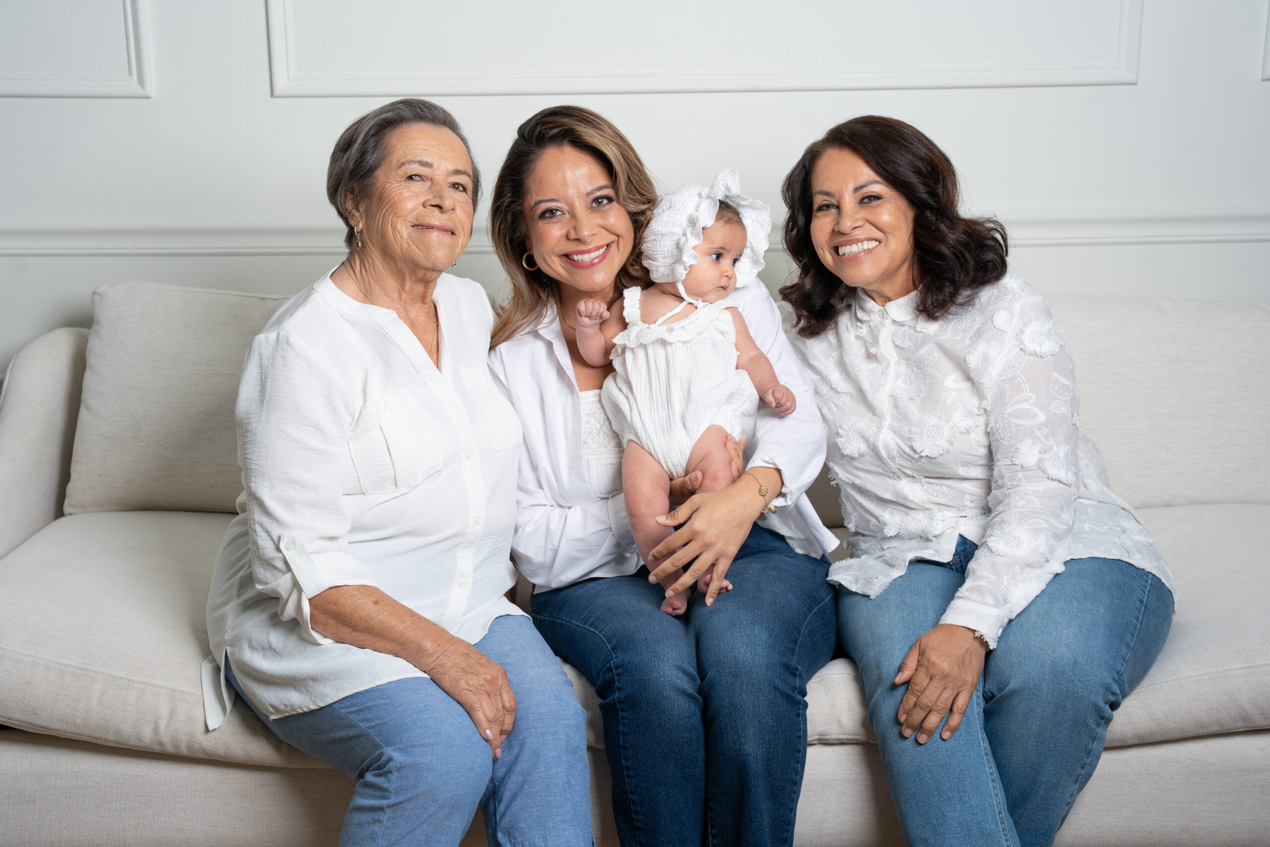Grandmother, mother and daughters on a sofa holding the baby, multi-generational portrait Long Island