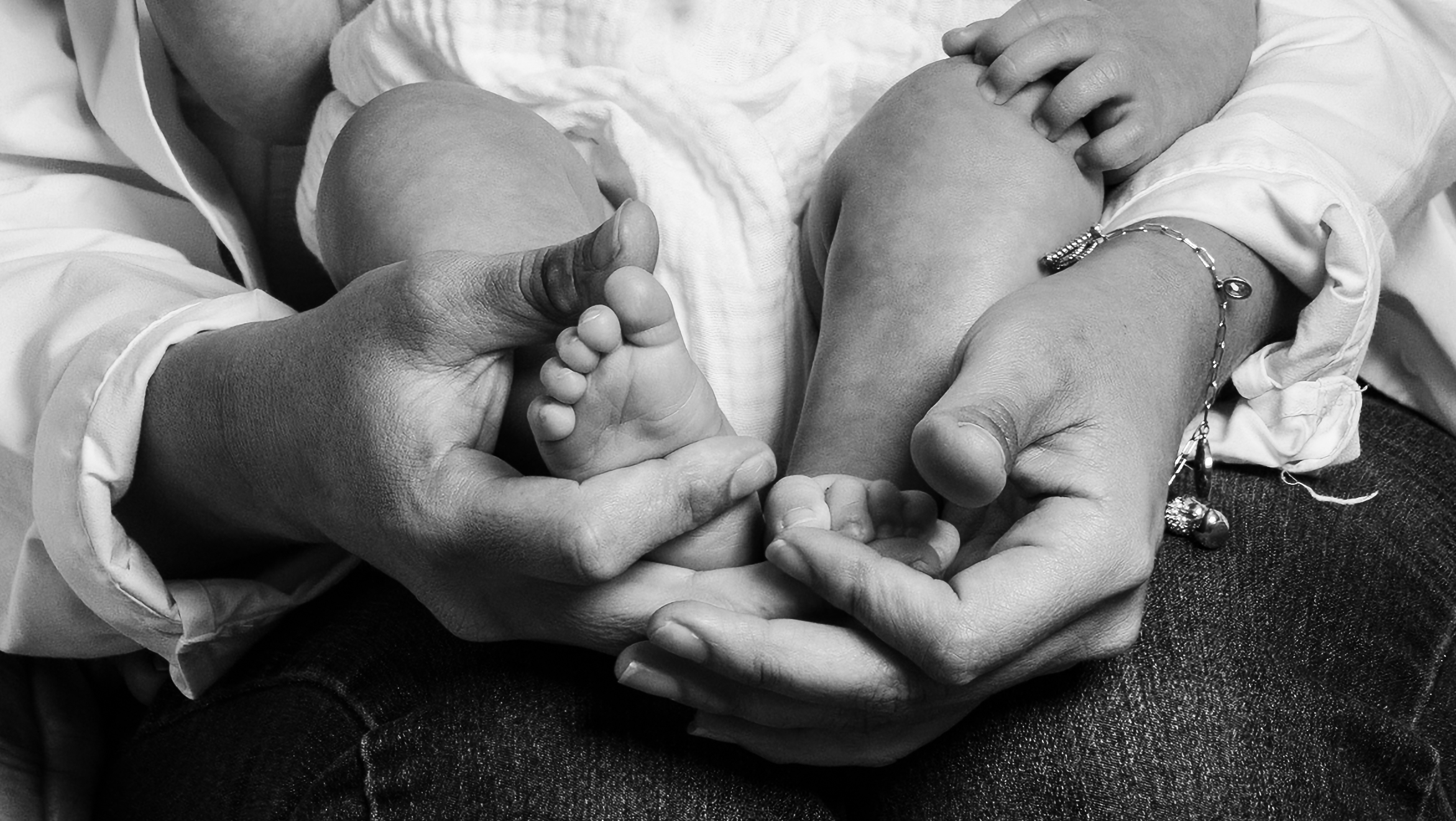 Black and white detail of hands holding baby feet, heirloom family portrait Long Island