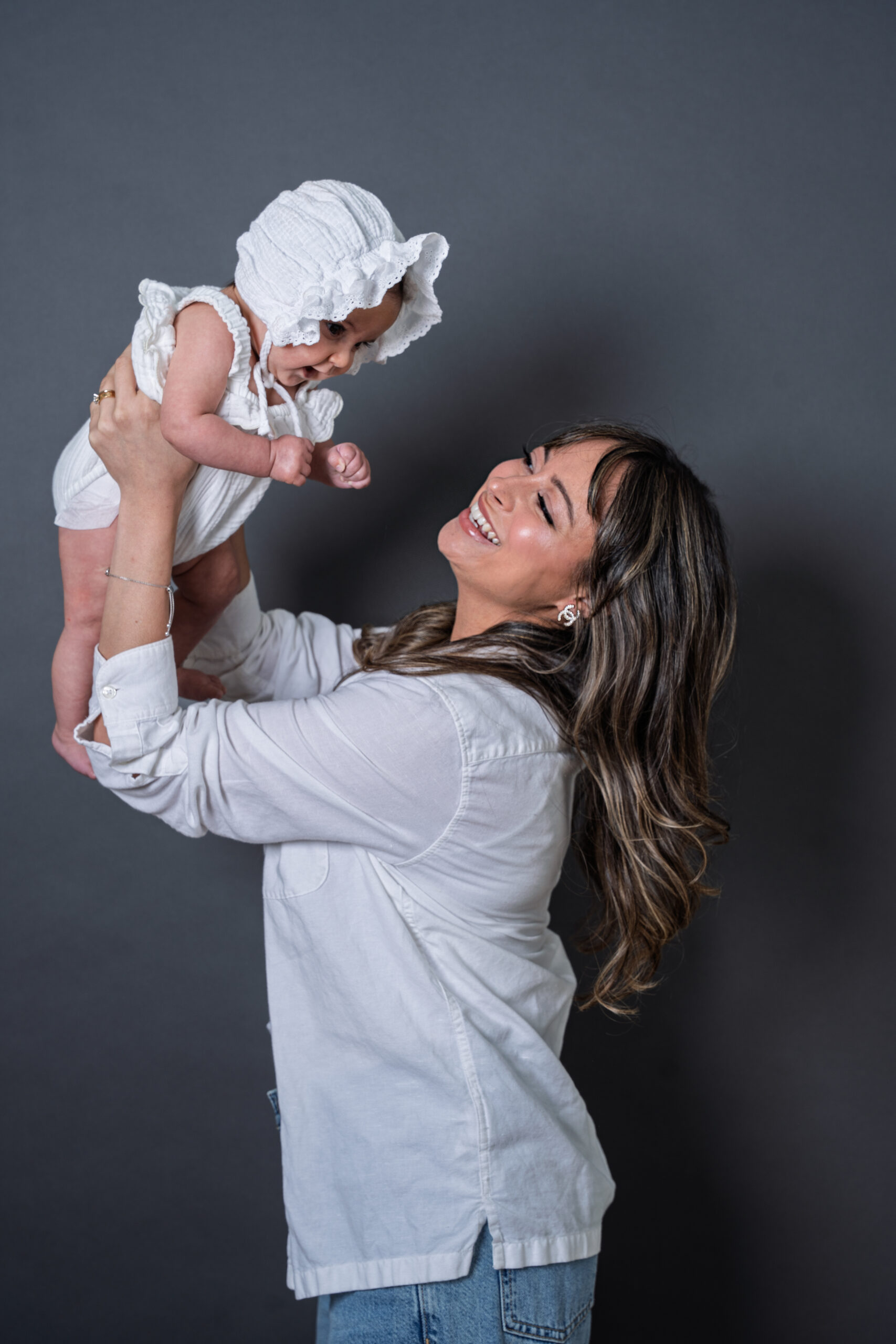 Mother lifting her baby girl in a white romper, family portrait session Long Island